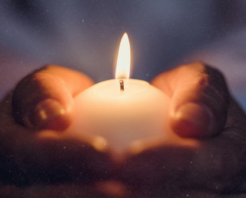 Wintersonnenwende feiern: Kerze in Händen unter Sternenhimmel symbolisiert die Rückkehr des Lichts