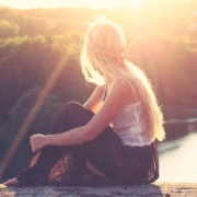 Frauen in der Bibel Frau sitzt barfuß am See im Sonnenuntergang, Sinnbild für Frauen in der Bibel und ihre zeitlose Kraft